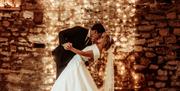 Bridal couple kissing in front of fairy lights at Eden Barn in Kirkby Stephen, Cumbria