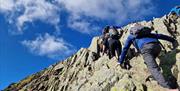Visitors Hiking Helvellyn via Striding & Swirral Edge with Guided Outdoors in the Lake District, Cumbria