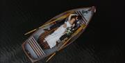 Drone Shot of Bridal Couple posing in a Rowboat at a Wedding at The Gilpin Hotel & Lake House in Windermere, Lake District