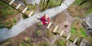 Child Crossing a Rope Bridge Looks up at Camera at Go Ape in Whinlatter Forest Park in Braithwaite, Lake District