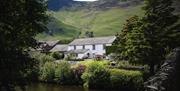 Exterior view from over the river of Grange Bridge Cottage in Borrowdale, Lake District