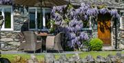 Exterior of Stone Cottage in Patterdale, Lake District with Wisteria and outdoor patio seating