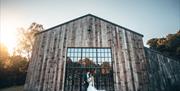 Bride and groom posing for a photo in front of Hidden River Barn near Longtown, Cumbria