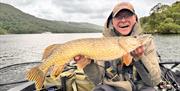 Visitor posing with fish caught on a fishing trip with West Pennine Angling Solutions in the Lake District, Cumbria