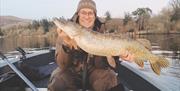 Visitor posing with fish caught on a fishing trip with West Pennine Angling Solutions in the Lake District, Cumbria
