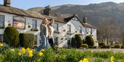 Couple walking with daffodils in front of The Swan at Grasmere in the Lake District, Cumbria