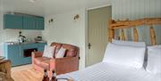 Interior of Juniper Lodge, with double bed, couch, and kitchenette at Coniston Shepherd Hut Lodges in Coniston, Lake District