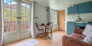 Interior of Juniper Lodge, with dining setup, kitchenette, and couch at Coniston Shepherd Hut Lodges in Coniston, Lake District