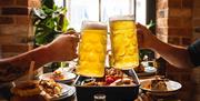 Visitors Toasting Beers over a Table with Food at Lake View Garden Bar in Bowness-on-Windermere, Lake District