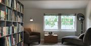 Bookshelf and lounge chairs at The Cottage at Linden Farm House in Langwathby, Cumbria