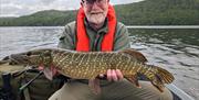 Visitor posing with fish caught on a fishing trip with West Pennine Angling Solutions in the Lake District, Cumbria