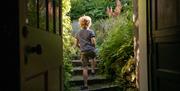 Child stepping into the gardens at Wordsworth Grasmere in the Lake District, Cumbria © Tom McNally