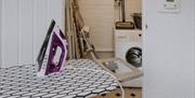Iron and ironing board, with utility and washing machine in the background at The Pheasant Lodge near Grange-over-Sands, Cumbria