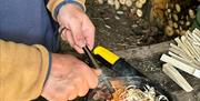 Visitor starting a fire at a bushcraft experience with Graythwaite Adventure Near Hawkshead, Lake District