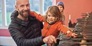 Father and child interacting with a xylophone exhibit at Keswick Museum in Keswick, Lake District