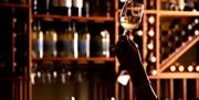 Person inspects a glass of wine in the wine cellar at The Borrowdale Hotel in Borrowdale, Lake District
