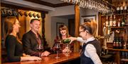 Staff pours wine at the bar for guests at The Borrowdale Hotel in Borrowdale, Lake District