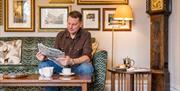 Guest reads a newspaper with coffee at The Borrowdale Hotel in Borrowdale, Lake District