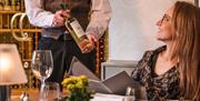 Guest receiving a bottle of wine from staff at The Borrowdale Hotel in Borrowdale, Lake District