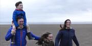 Family for a walk on the sands at Holgates Holiday Park in Silverdale, Cumbria
