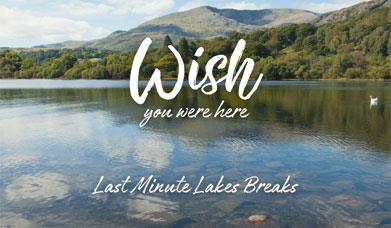 Text that reads "Wish you were here, Last Minute Lakes Breaks" over a calm photo of a lake and hills