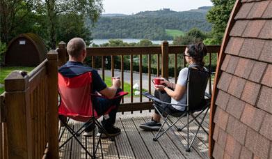Couple admiring the view from the balcony of a glamping pod at Park Cliffe