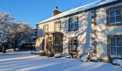 Farlam Hall Hotel in the wintertime with snow covered drive and foliage