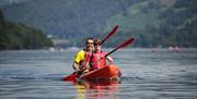 Two Visitors Smiling from a Kayak from Windermere Canoe Kayak in the Lake District, Cumbria