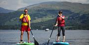 Two Visitors Paddleboarding at Windermere Canoe Kayak in the Lake District, Cumbria