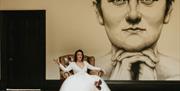 Bride Posing in an Armchair in front of a Portrait of Beatrix Potter at a Wedding at Allan Bank in Grasmere, Lake District