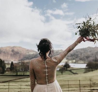 Bride with Raised Bouquet Overlooking Scenic Views from a Wedding at Allan Bank in Grasmere, Lake District
