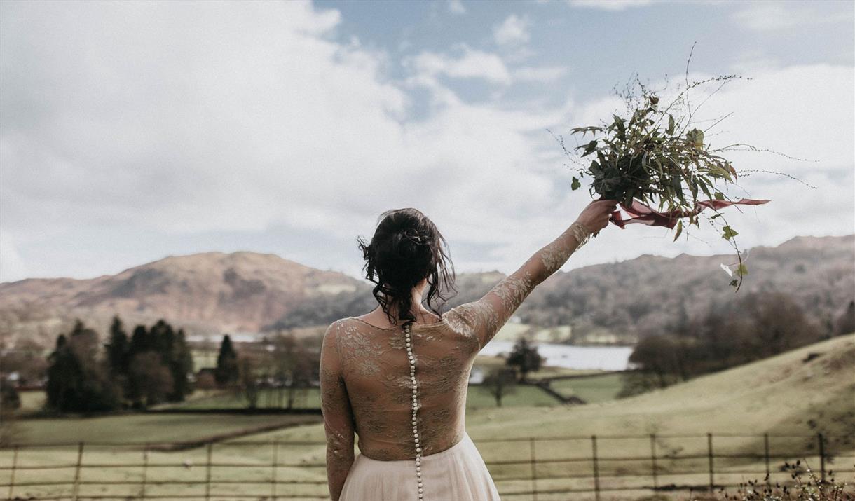 Bride with Raised Bouquet Overlooking Scenic Views from a Wedding at Allan Bank in Grasmere, Lake District