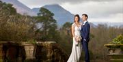 Happy Couple Posing for Wedding Photos with Mountain Backdrop at Armathwaite Hall Hotel and Spa in Bassenthwaite, Lake District