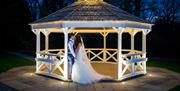 Happy Couple Posing for Wedding Photos in a Gazebo at Armathwaite Hall Hotel and Spa in Bassenthwaite, Lake District
