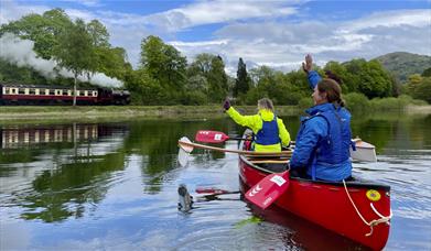 Canoeists wave at the steam train