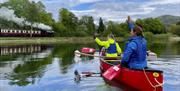 Canoeists wave at the steam train