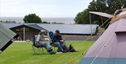 Visitors Sitting Outside Pitched Tents at Hollins Farm Holiday Park in Far Arnside, Cumbria