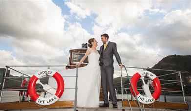 Just married couple standing on Lady of the Lake heritage vessel, Ullswater 'Steamers' Cumbria.