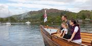 Family looks Out on Lake Windermere from the Bow of a Boat in the Lake District, Cumbria