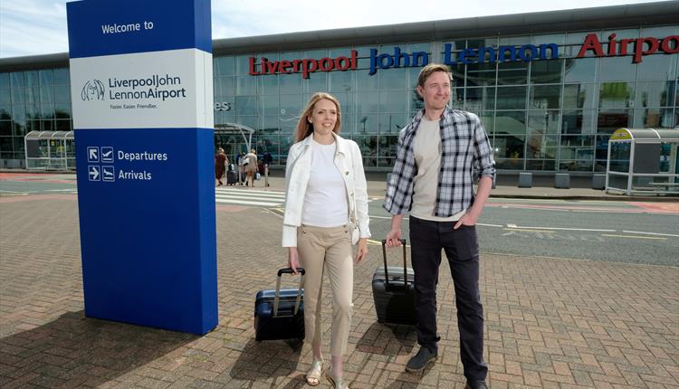 two passengers outside the front of the airport terminal