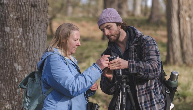 Man teaching woman how to use her DSL camera.