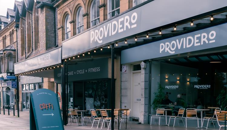 The picture of the outside of Providero's Llandudno coffeehouse with outdoor seating and an aboard that says "coffee"