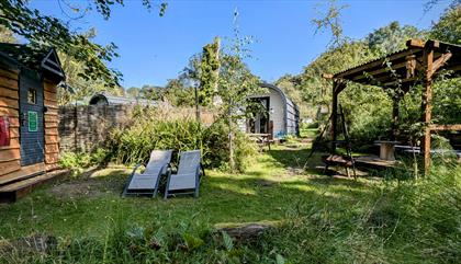 View of the Orme glamping pod gardens with outdoor undercover seating and a Finnish Sauna