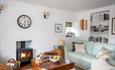 Comfortable living room with a wood-burning stove, sofas, wooden coffee table and bookshelves, creating a cosy space to unwind after a day exploring.