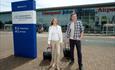 two passengers outside the front of the airport terminal