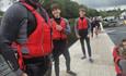 Father and two teenage sons standing together on a pontoon at Llyn Padarn Lake, North Wales, dripping with water and smiling after a refreshing jump i