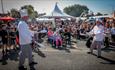 A pair of entertainers dressed up as chefs juggling between them as the crowds watch on behind them in the sunshine.
