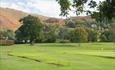 Golf course with trees and mountains in distance