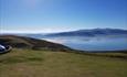 This image is a view from the Great Orme Llandudno showing the calm sea, blue skies and rolling hills