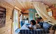 A couple relax in the interior of the Ayr Glamping Pod at Emlyn's Coppice in Flintshire